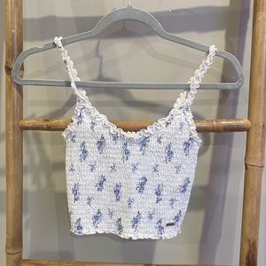 White with floral pattern holister tank/crop top. Ribbed material and ruffle hem